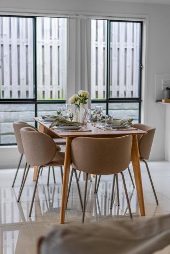 a dining room table with chairs and a table centerpiece at Whispering Pines - Stylish 3BR Duplex close to M1 in Pimpama