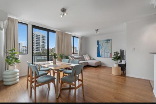 a living room with a table and chairs and a couch at Central urban nest with pool gym pool free parking in Perth