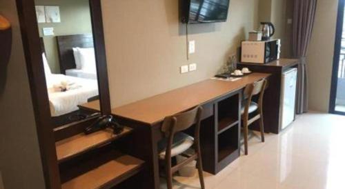 a room with a vanity with a mirror and a bed at Wsotel Hotel in Songkhla