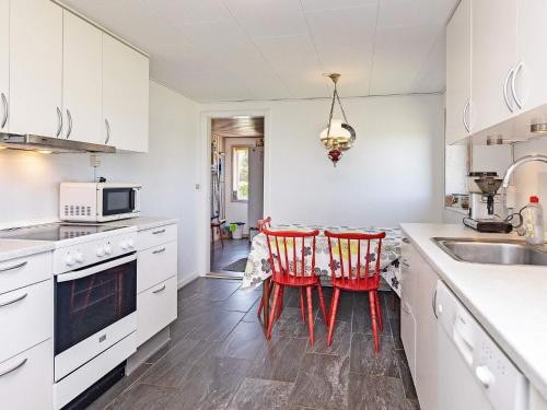 a kitchen with white cabinets and red chairs at 10 person holiday home in Vinderup-By Traum in Vinderup