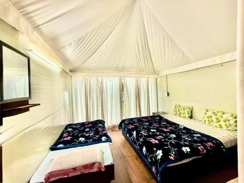 a bedroom with two beds in a white tent at Ambler Spaces in Banethi