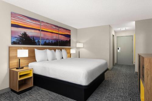 a hotel room with a bed and a painting on the wall at Days Inn by Wyndham Rawlins in Rawlins