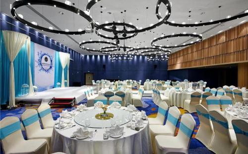 a banquet hall with white tables and chairs and a chandelier at New Century Kylie Hotel Ningbo in Ningbo