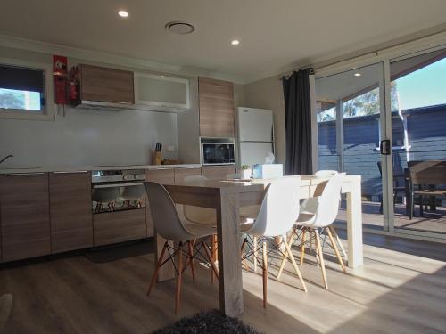 a kitchen with a dining table and white chairs at Dungowan Holiday Accommodation in Erowal Bay