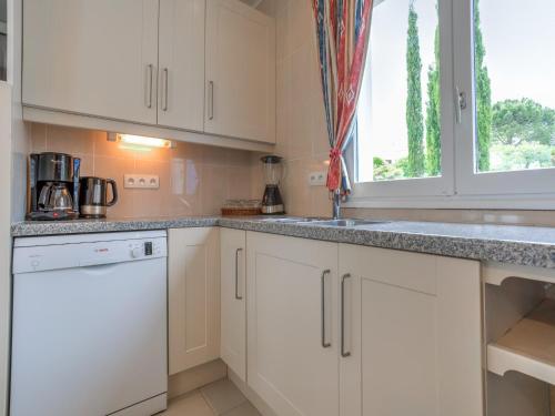 a kitchen with white cabinets and a sink and a window at Modern villa with private pool in Pouzols-Minervois