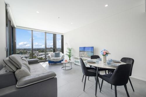 a living room with a couch and a table with chairs at Olympic Park Stylish Apt with Gym Pool great view in Sydney