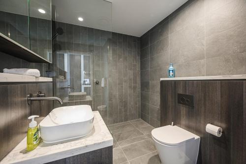 a bathroom with a sink and a toilet in it at Olympic Park Stylish Apt with Gym Pool great view in Sydney