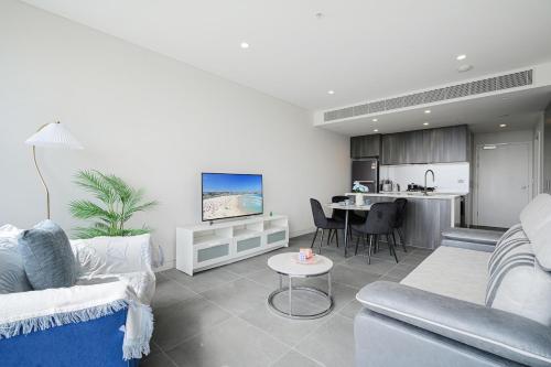 a living room with a couch and a table and a kitchen at Olympic Park Stylish Apt with Gym Pool great view in Sydney