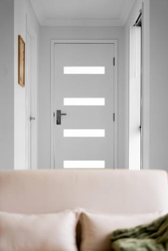 a white couch in front of a door at Scandi Calm - Sleek 1BD Duplex near Everything in Pimpama