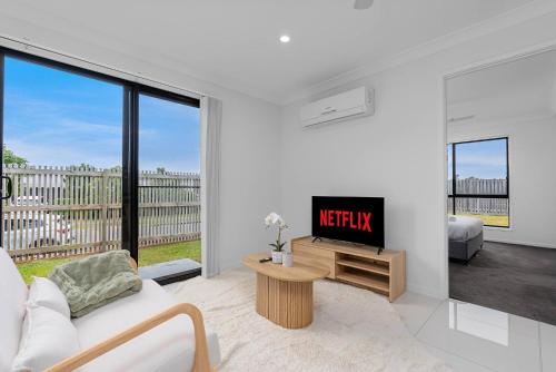 a living room with a couch and a tv at Scandi Calm - Sleek 1BD Duplex near Everything in Pimpama