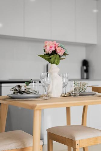 a table with plates and a vase with pink flowers at Scandi Calm - Sleek 1BD Duplex near Everything in Pimpama