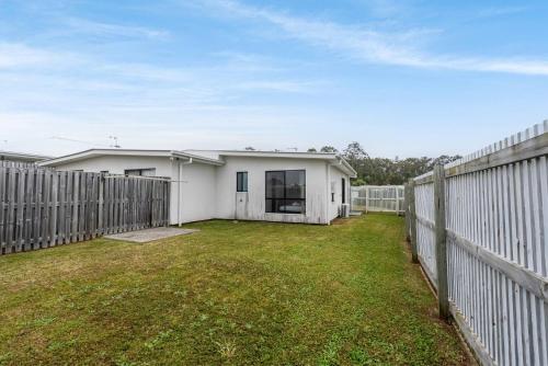 a white house with a fence in a yard at Scandi Calm - Sleek 1BD Duplex near Everything in Pimpama