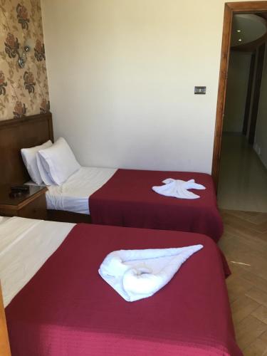 two beds in a hotel room with towels on them at Abeer Hotel Alexandria in Alexandria