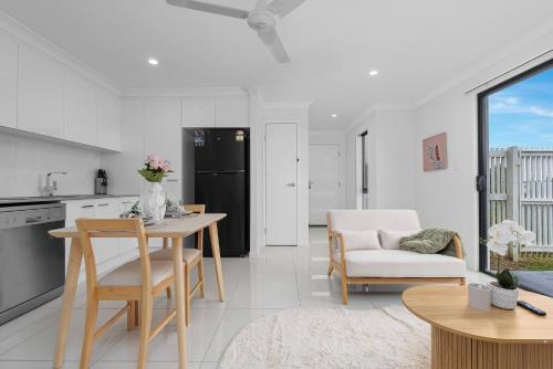 a kitchen and living room with a table and chairs at Scandi Calm - Sleek 1BD Duplex near Everything in Pimpama