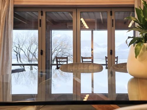 a room with glass doors and a table and chairs at Whare Puwaha - River Mouth House in Glenorchy