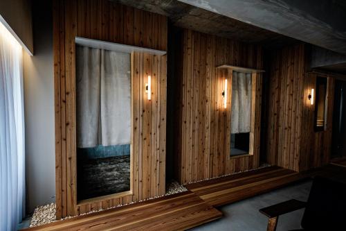 a room with wooden walls and two windows with lights at Alternest Kamakura in Kamakura