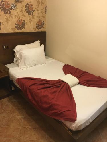 a bed with a red blanket on top of it at Abeer Hotel Alexandria in Alexandria