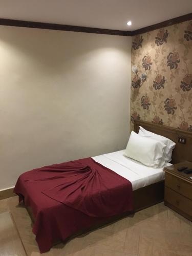 a bedroom with a bed with a red blanket at Abeer Hotel Alexandria in Alexandria