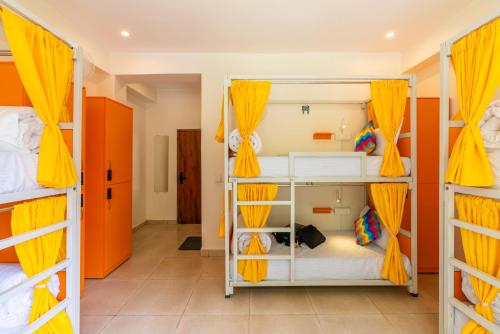 a room with four bunk beds with yellow curtains at goSTOPS PLUS Kasol, Suma Ropa in Kasol