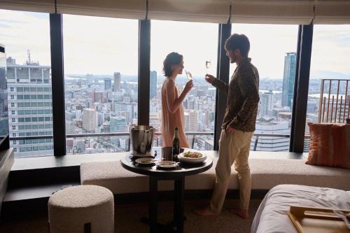 a man and a woman standing in a room with a window at Four Seasons Hotel Osaka in Osaka
