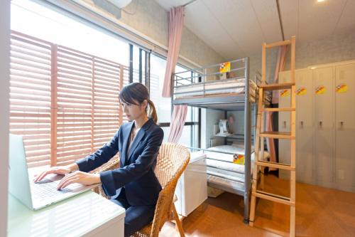 a woman sitting at a desk using a laptop computer at Akasaka-no Sato (Female Only) in Tokyo