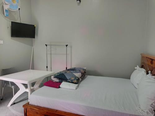 a bedroom with a white bed with a table at Haven Guest House, Kasese in Kasese