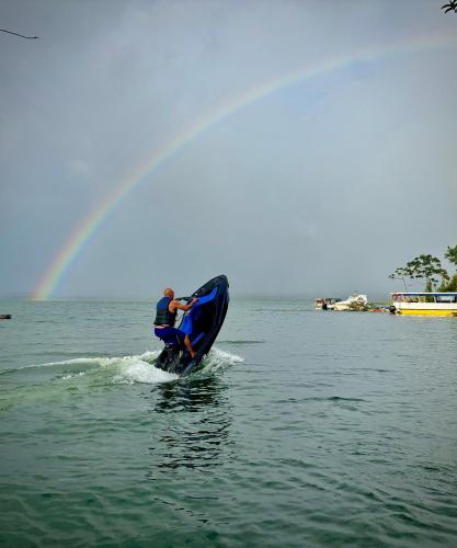 a man on a jet ski in the water with a rainbow at Cabañas Litos #3 in Fortuna