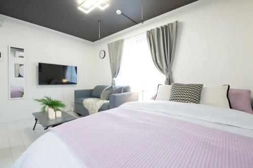 Un dormitorio blanco con una cama grande y un sofá. en 渋谷区代々木302, en Tokio