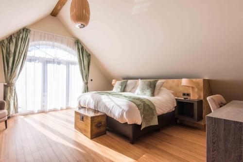 a bedroom with a bed and a large window at Koru Hôtel & Private Wellness in Autre-Église