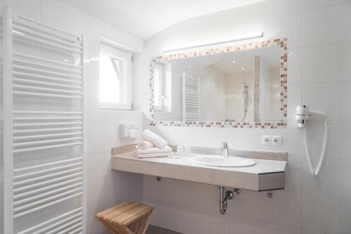 Baño blanco con lavabo y espejo en Gasthof Edelbrunn en Ramsau am Dachstein