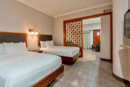 a hotel room with two beds and a living room at Wyndham Garden Baronne Plaza in New Orleans