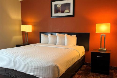 a large bed in a hotel room with two lamps at Baymont by Wyndham Plainfield/ Indianapolis Arpt Area in Plainfield