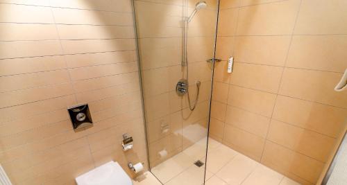 a shower with a glass door in a bathroom at Best Western Plus Hotel Ostertor in Bad Salzuflen