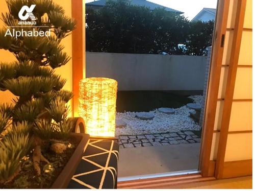 a glass door leading into a garden with a light at Alphabed Takamatsukouzaiekimae 102 / Vacation STAY 20340 in Takamatsu