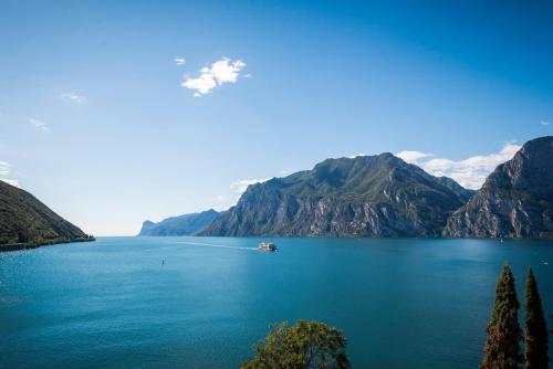 a boat on a lake with mountains in the background at Torbole Aparthotel in Nago-Torbole