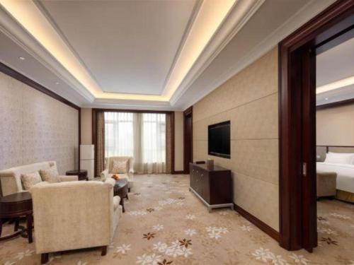 a hotel room with a bed and a television and a living room at Linyi Blue Horizon International Hotel Yi He in Linyi