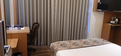 a hotel room with a bed and a desk and a window at Shine Hospitality Premium in Mumbai