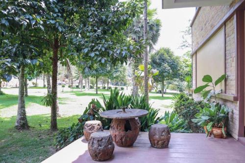 a table and stools on a patio with trees at OYO 742 View Pruksa Resort in Ranong