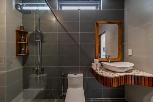 a bathroom with a sink and a mirror and a shower at HON BA LAGI BEACH RESORT in La Gi