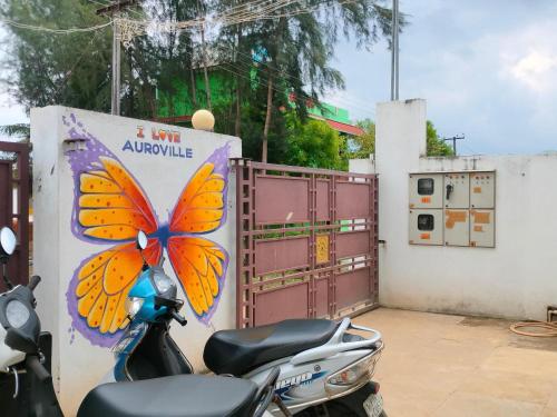 un scooter garé à côté d'une porte avec un papillon peint dessus dans l'établissement Funk Monk hostel visitors centre auroville, à Auroville