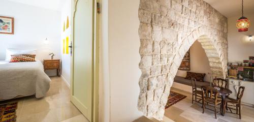 a bedroom with a stone wall next to a bed and a table at The Way Inn - Boutique Suites in Safed