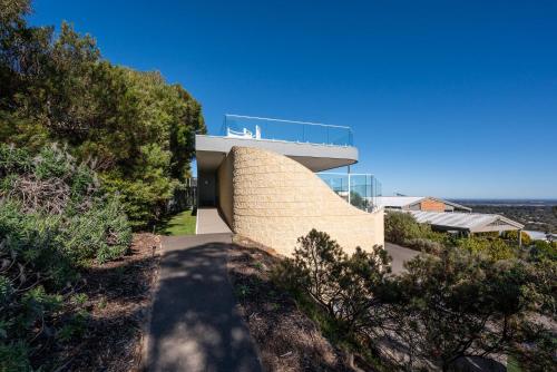 a house on a hillside with a glass building at Horizons on Hove with Heated Spa in Rosebud
