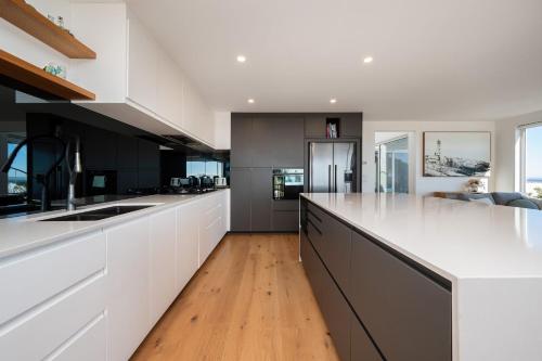 a large kitchen with white cabinets and a wooden floor at Horizons on Hove with Heated Spa in Rosebud