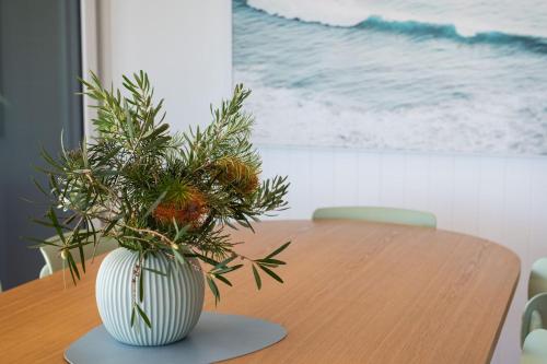 a wooden table with a vase with a plant in it at Horizons on Hove with Heated Spa in Rosebud