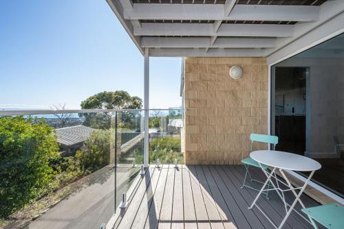 a patio with a table and chairs on a balcony at Horizons on Hove with Heated Spa in Rosebud