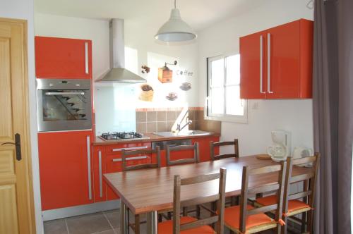 une cuisine avec des placards rouges et une table en bois dans l'établissement Whitley cottage, à Condette