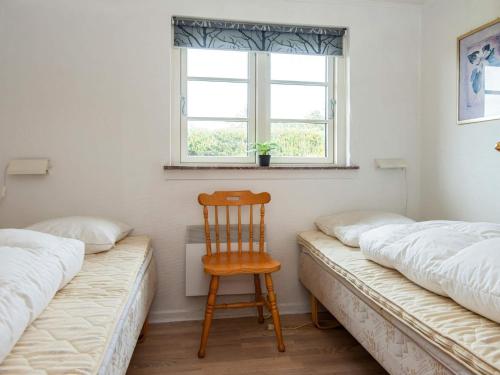 a bedroom with two beds and a wooden chair at Luxury Seaside Retreat - By Traum Ferienwohnungen in Fjand Gårde
