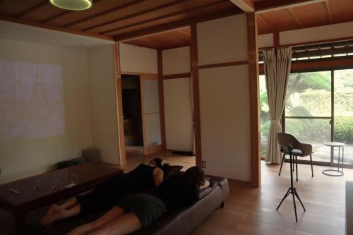two people laying on a couch in a living room at ISHIZUCHI Villa HANA in Saijo