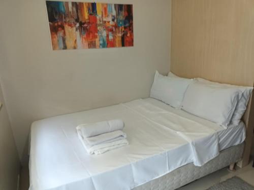 een wit bed met twee witte handdoeken erop bij Dvine Era Staycation in Manilla