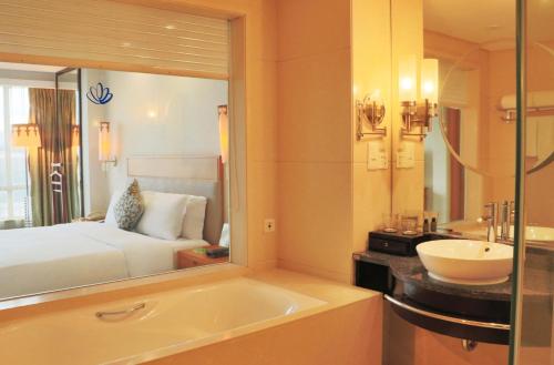 a bathroom with a tub and a bed and a sink at Dongguan Well Garden Hotel in Dongguan